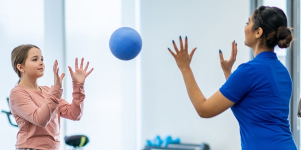 a young woman and a therapist playing with a ball