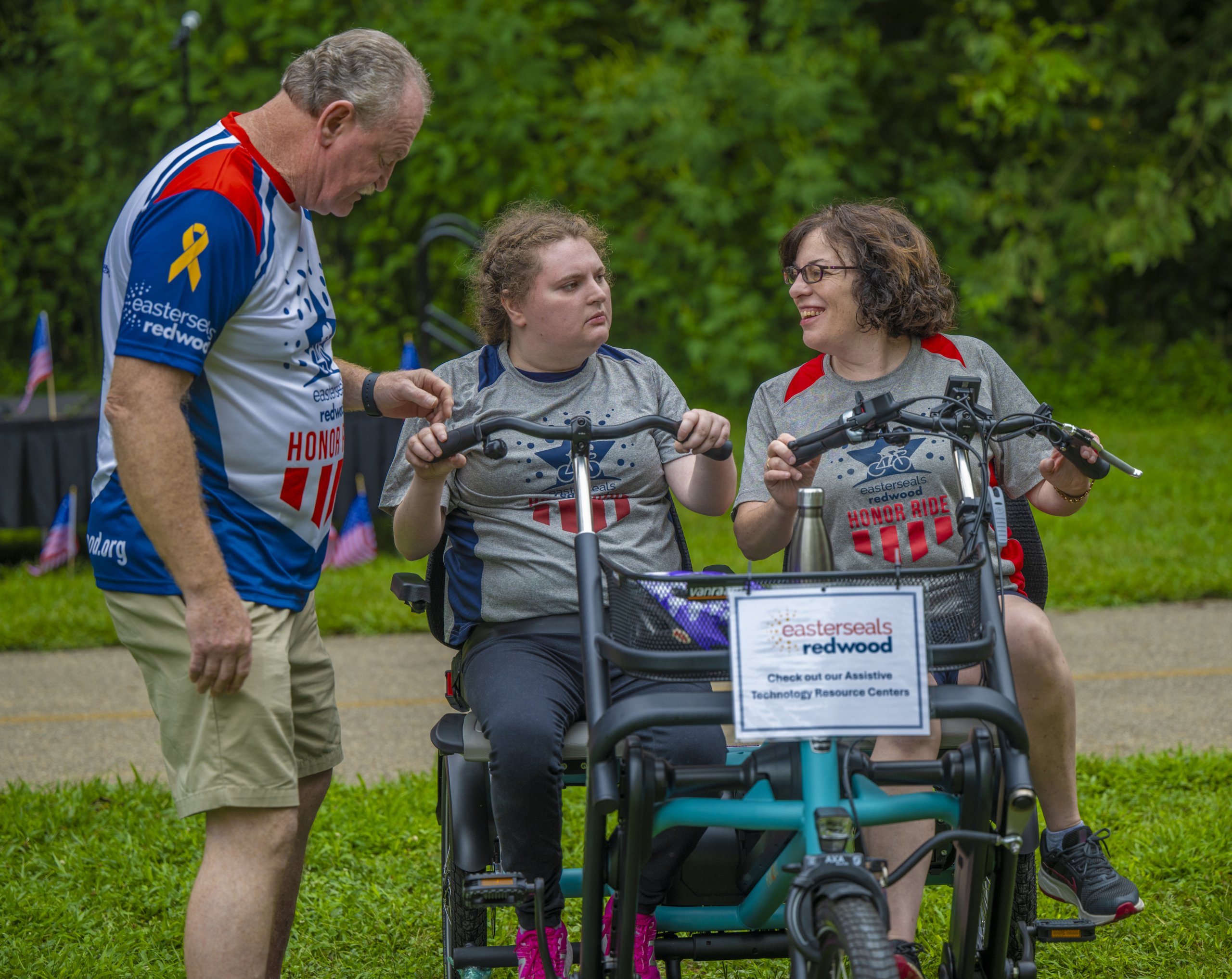 A man assists two women on an adaptive bike during Honor Ride.
